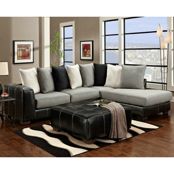 Idol Steel Sectional. It features sleek track arms and a streamlined base, all covered in black Durahide with white contrast stitching. The supportive cushions are upholstered in a soft, contrasting gray microfiber to give this sofa a contemporary two-tone look.