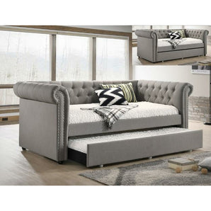 Ellie Daybed in Grey. The soft, padded frame is upholstered in a beige fabric, with button tufting at the inside back and sides. Includes rolling arms with nailhead trim on the front for a truly elegant look. 